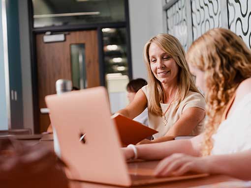 Two people working on laptop at table